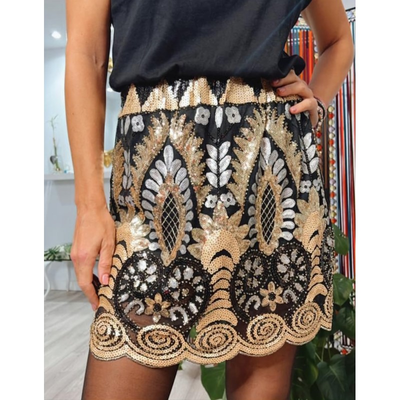 Vista más de cerca de detalles dorados de lentejuelas en falda corta negra, vista por delante.