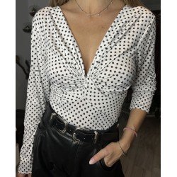 Body de manga larga blanco con topos negros, de escote de pico, visto pir delante.