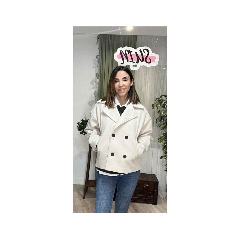 Chaqueta con botones y solapa de color blanco roto y está abrochada.