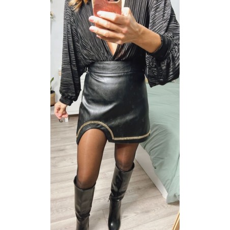 Falda negra corta, de polipiel, con ribete dorado abajo, vista por delante.